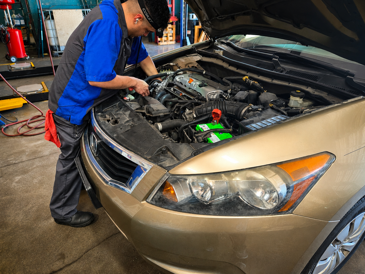 Technician working under the hood of a sedan at Auto Care USA Briar Forest in Houston, TX