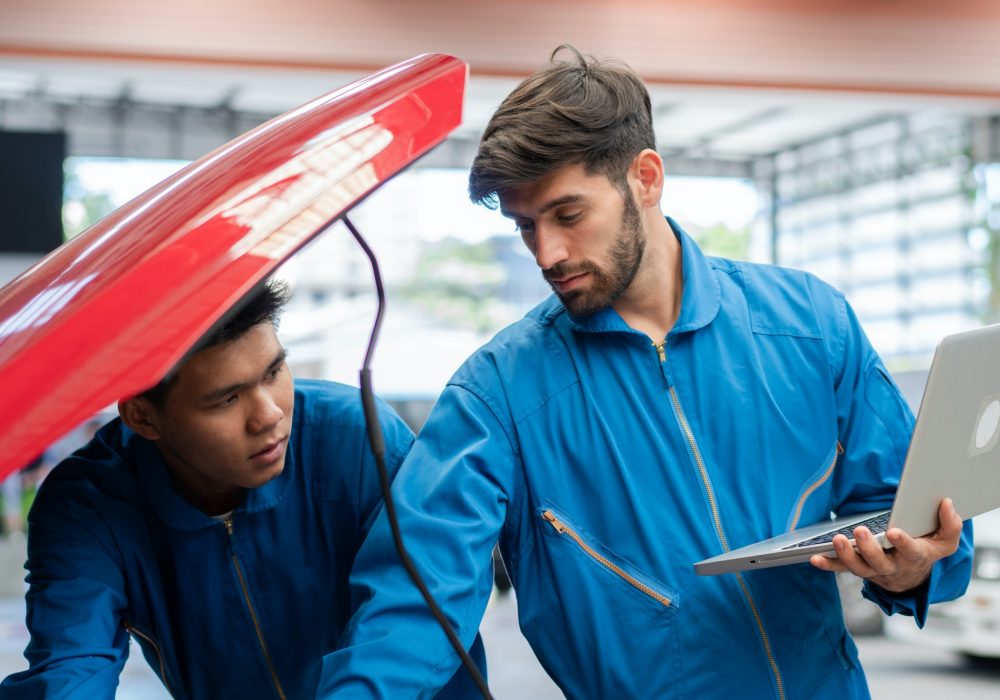 car-mechanic-team-using-laptop-boosting-car-engine-at-auto-repair-shop.jpg