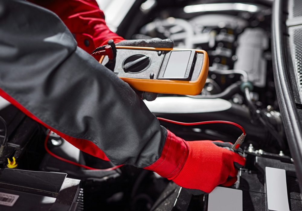 Crop male technician checking car battery