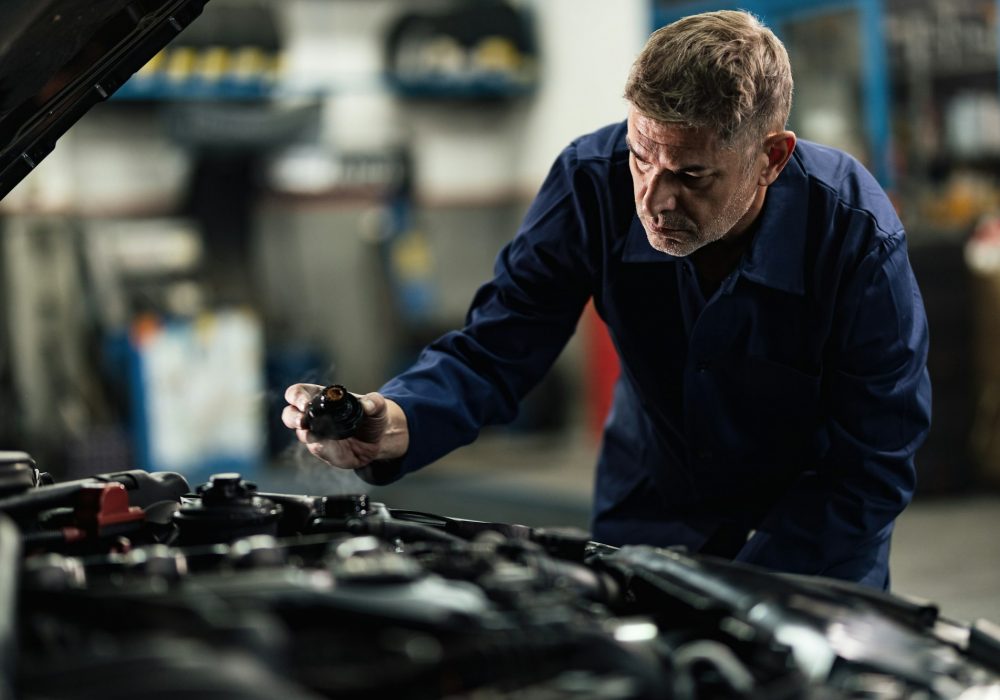 Mid adult mechanic checking overheated car coolant system in a garage.