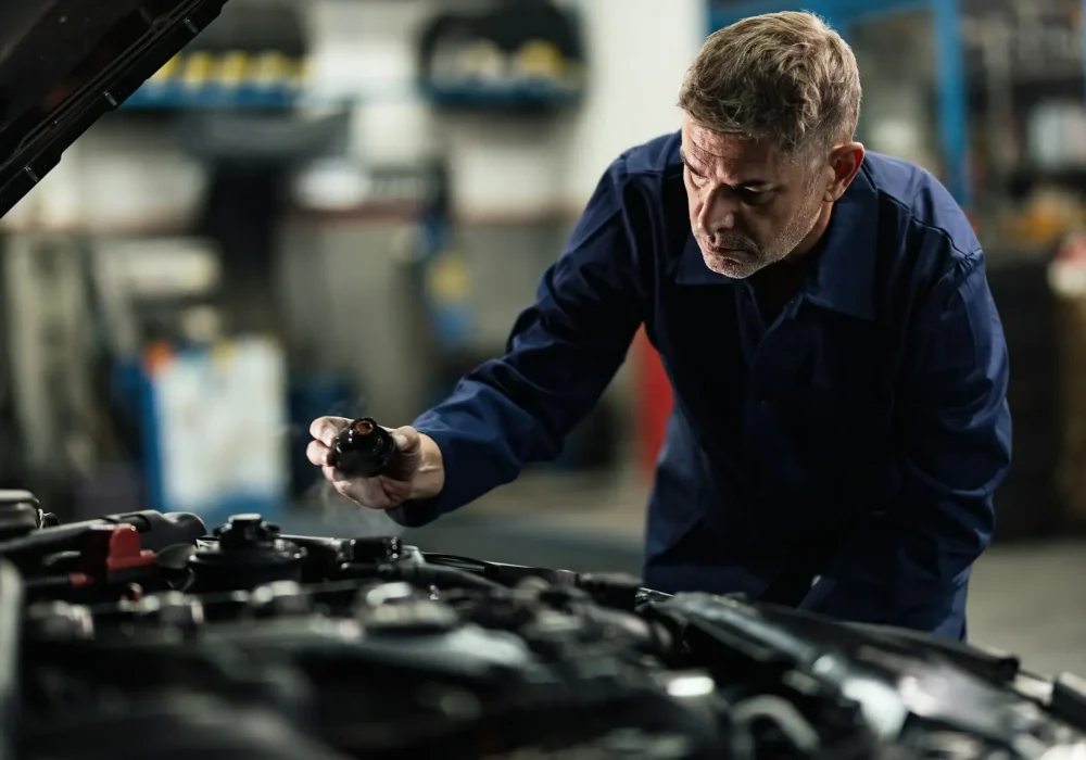 Mid adult mechanic checking overheated car coolant system in a garage.